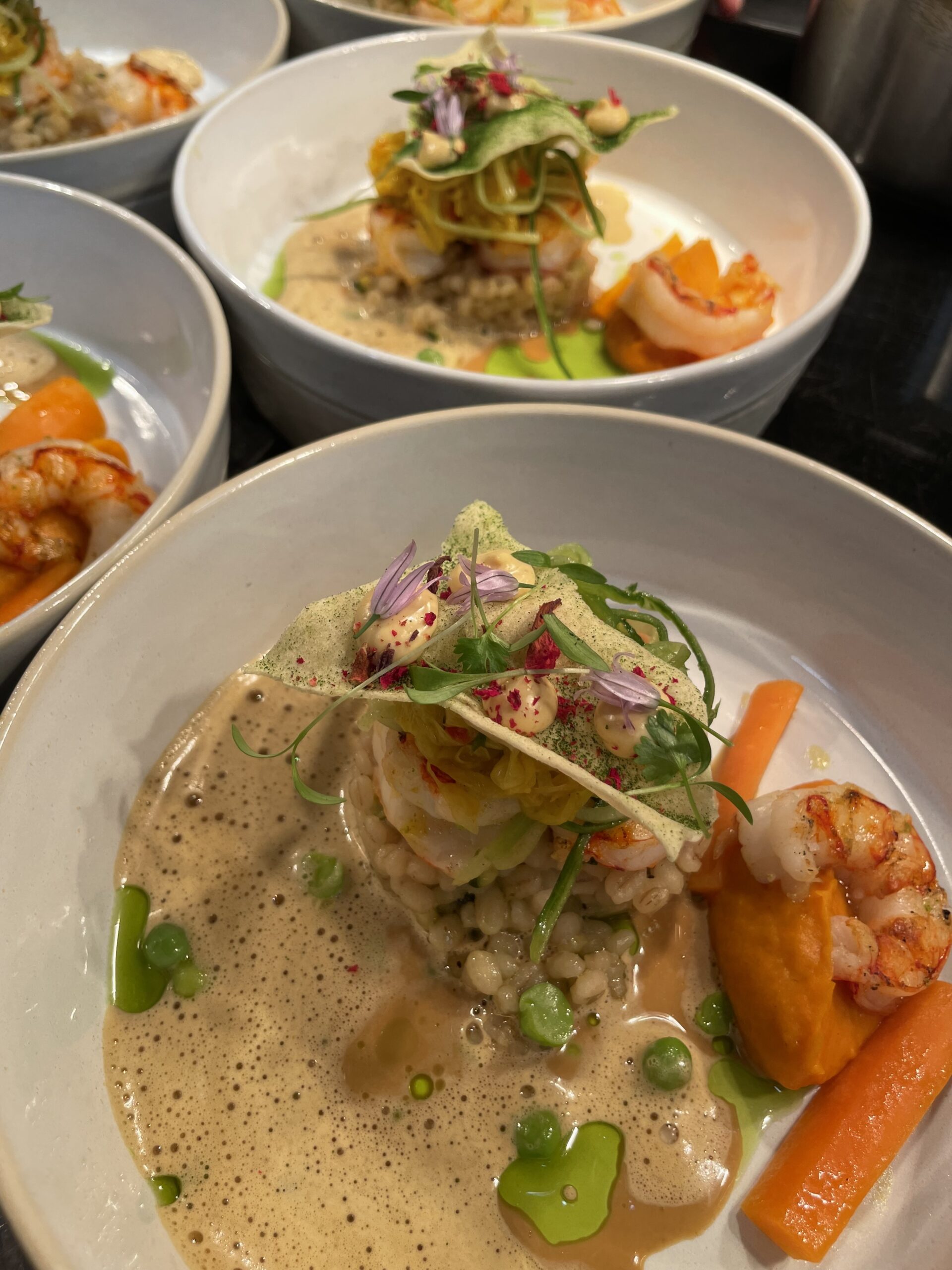 Voorgerecht met gamba, parelgort, wortel en schuimige saus in diep bord