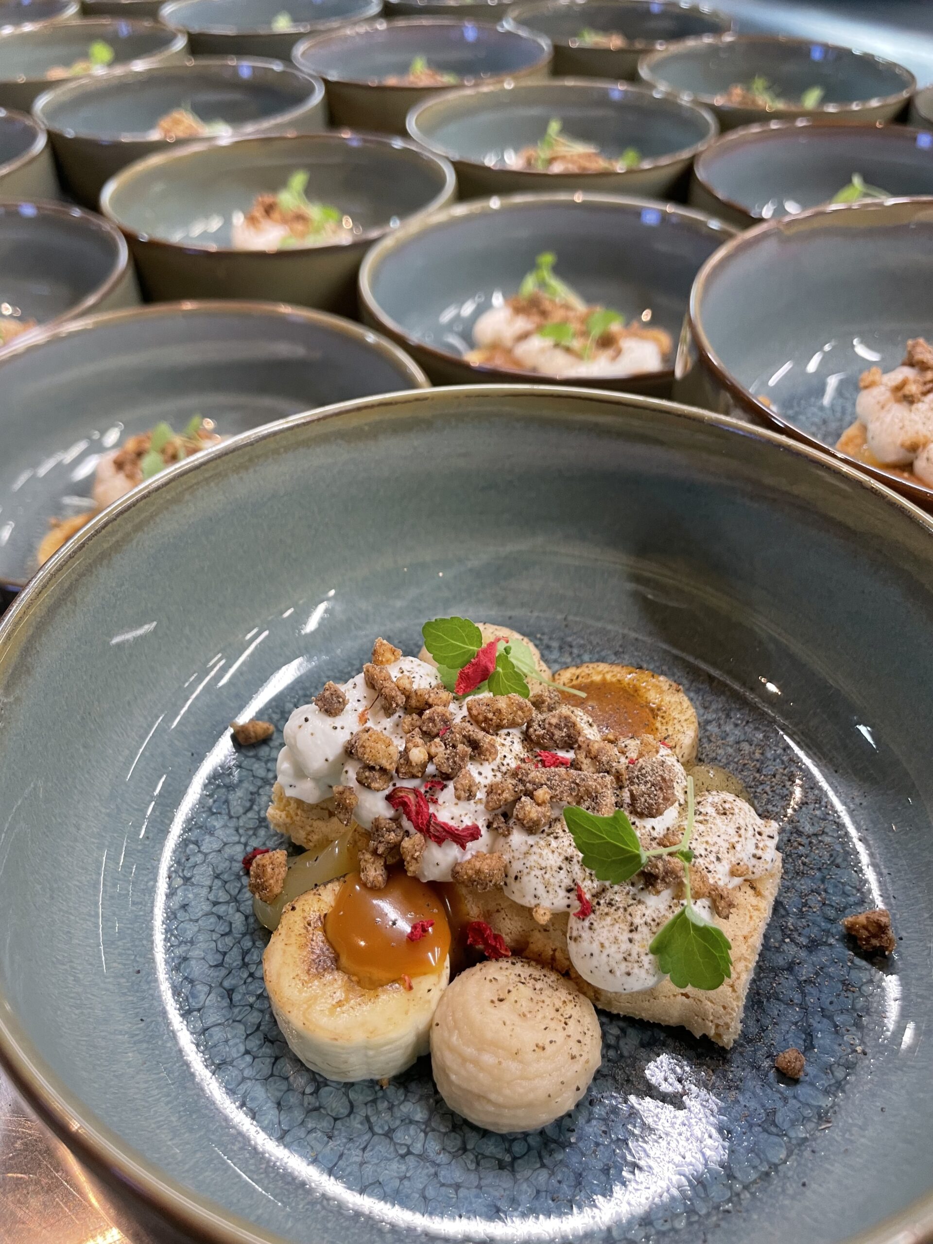 Dessert met banaan, crème, crumble en munt in blauw bord